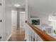 Upstairs hallway with wood floors, open railing and view into a bedroom at 6150 Half Moon Dr, Port Orange, FL 32127