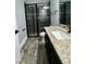 Modern bathroom with granite counters, wood look tile floor and black framed glass enclosed shower at 6301 Swanson St, Windermere, FL 34786