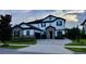 Charming two-story home featuring stone accents, a paved driveway, manicured landscaping, and a dark-colored roof at 6301 Swanson St, Windermere, FL 34786