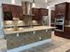 A kitchen featuring stainless steel appliances, tile backsplash, large island and dark wood cabinets at 6301 Swanson St, Windermere, FL 34786