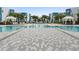 Modern pool with light colored pavers, cabanas, and lounge chairs, surrounded by palm trees and blue-trimmed apartments at 7740 Sandy Ridge Dr # 206, Kissimmee, FL 34747
