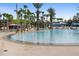 Expansive community pool perfect for swimming and lounging with surrounding palm trees, lounge chairs, and a bar at 7740 Sandy Ridge Dr # 206, Kissimmee, FL 34747