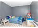 Comfortable bedroom features light carpet, a blue bed, gray walls, and a white side table at 893 S Dean Cir, Deltona, FL 32738