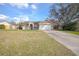 Tan single-story home featuring an attached two-car garage and a well-maintained front yard and long driveway at 893 S Dean Cir, Deltona, FL 32738