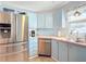 Bright kitchen with stainless steel appliances, including a refrigerator and dishwasher, plus blue cabinets and a double sink at 907 Rose Ln, The Villages, FL 32159