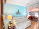 Inviting living room with wood floors, light blue accent wall, and comfortable white sofa at 907 Rose Ln, The Villages, FL 32159