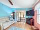 Bright living room with wood floors, light blue accent wall, and comfortable white sofa at 907 Rose Ln, The Villages, FL 32159