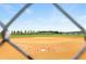 Well-maintained community baseball field viewed through a chain-link fence, showcasing a green outfield and clear blue skies at 9580 Sw 71St Loop, Ocala, FL 34481