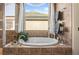 A close up of the soaking tub with tile surround, decorative accents, and a window providing natural light in the bathroom at 9580 Sw 71St Loop, Ocala, FL 34481