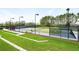 Well-maintained tennis court featuring lighting, secure fencing and surrounding green grass at 9580 Sw 71St Loop, Ocala, FL 34481
