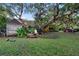 Serene backyard featuring mature trees, manicured lawn, and a cozy shed with a seating area at 120 Beach St, Ponce Inlet, FL 32127