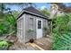 Charming backyard shed with shuttered windows and a white door, nestled in a lush garden setting at 120 Beach St, Ponce Inlet, FL 32127