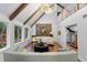 Bright living room with vaulted ceilings, wooden beams, modern chandelier, and picture windows overlooking lush greenery at 120 Beach St, Ponce Inlet, FL 32127