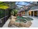 Enclosed pool with rock waterfall and jacuzzi, surrounded by lush tropical landscaping and open to the home through sliding glass doors at 120 Beach St, Ponce Inlet, FL 32127