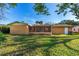 View of the home's backyard, with a screened-in porch and lush green lawn and mature landscaping at 1216 Sunland Rd, Daytona Beach, FL 32114