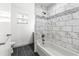 This bathroom features a toilet and a tub/shower combo with white and gray tiling and dark floors at 1216 Sunland Rd, Daytona Beach, FL 32114