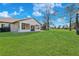 Expansive backyard with lush green lawn, mature trees, and a covered patio at 1924 Seclusion Dr, Port Orange, FL 32128