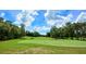 Scenic golf course with lush green fairways and mature trees creating a picturesque landscape and a golf cart at 205 Victoria Trails Blvd, Deland, FL 32724
