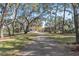 Long brick driveway leads to a beautiful home with lush trees, creating a private and serene atmosphere at 2111 Hontoon Rd, Deland, FL 32720