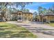 Elegant two-story home with a circular driveway, detailed stonework, and a porte cochere leading to a detached garage at 2111 Hontoon Rd, Deland, FL 32720
