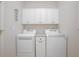 Well-lit laundry room featuring a modern washer and dryer set and matching white cabinets for ample storage at 215 Coleton Ln, Deland, FL 32724