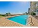 Inviting outdoor pool surrounded by lounge chairs, lush landscaping, and partial ocean views at 2403 S Atlantic Ave # 209, Daytona Beach Shores, FL 32118