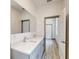 Bathroom with double vanity, quartz countertop, large mirror, wood-look flooring and an open doorway at 28 Guava Ln, Ocklawaha, FL 32179