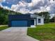 One-story home with blue garage door and door, gray and blue exterior paint, green lawn, and cloudy skies at 28 Guava Ln, Ocklawaha, FL 32179