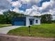 Charming one-story home with blue garage door, gray and blue exterior paint, and a well-manicured lawn at 28 Guava Ln, Ocklawaha, FL 32179
