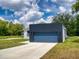 View of the two-car garage and front lawn at 28 Guava Ln, Ocklawaha, FL 32179