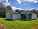 Back of the property with a covered patio and manicured lawn at 28 Guava Ln, Ocklawaha, FL 32179