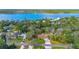 Aerial view of a home with a long driveway, green lawn, tall trees, and a nearby lake at 2910 Hardy Ave, New Smyrna Beach, FL 32168