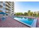 Outdoor pool with lounge chairs, tables, umbrella and a view of the surrounding palms and condo building at 3 Oceans West Blvd # 1D6, Daytona Beach Shores, FL 32118