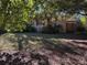 A single story home with mature trees and shrubs in the front yard with shadows of trees at 575 Lantern Ln, Orange City, FL 32763