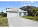 New construction home featuring a light blue exterior, metal roof, garage, and beautifully landscaped front yard at 72 Aurora Ave, Ponce Inlet, FL 32127