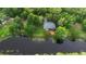 Aerial view of a property bordering a body of water, surrounded by dense greenery, and featuring a wooden deck at 725 E New York Ave, Orange City, FL 32763