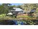 Back exterior featuring a screened-in porch, deck, and serene pond, perfect for outdoor living and entertaining at 725 E New York Ave, Orange City, FL 32763