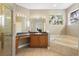 Bright bathroom featuring a glass-enclosed shower, large vanity, and a soaking tub by a window at 725 E New York Ave, Orange City, FL 32763