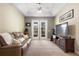 Comfortable living room featuring a plush sofa, TV, and access to the outdoor deck through French doors at 725 E New York Ave, Orange City, FL 32763