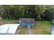 Aerial view of a small, light blue house with a metal carport and mature trees at 753 Glenwood Rd, Deland, FL 32720