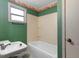 Retro bathroom featuring a green wall, white bathtub, and floral wallpaper border at 753 Glenwood Rd, Deland, FL 32720
