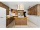 Well-lit kitchen with tile flooring, wood cabinetry, a center island, and a white refrigerator for a functional space at 753 Glenwood Rd, Deland, FL 32720