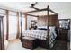 Spacious main bedroom with a four-poster bed, plush carpeting, and large windows with curtains at 12841 Se 97Th Terrace Rd, Summerfield, FL 34491