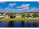 Waterfront backyard featuring a well-maintained lawn and mature trees with blue skies and white puffy clouds in the background at 1750 Savannah Ln, Port Orange, FL 32128