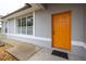 Inviting front entrance featuring a vibrant orange door, grey exterior, and manicured landscaping details at 1983 Stacey Cir, Deltona, FL 32738