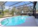 Screened-in pool with blue water, surrounded by an outdoor seating area and lush greenery at 2057 Hillview Circle, Deltona, FL 32738