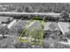 Monochrome aerial view of a home outlined in yellow, next to similar homes and a lush tree area at 212 Stonington Way, Deland, FL 32724