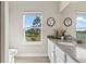 Bright bathroom with a large mirror, long countertop, and a window offering serene outdoor views at 2236 Oconnel Dr, Ormond Beach, FL 32174