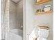 Bright bathroom features a tub with tiled wall and floating shelves for ample storage at 2236 Oconnel Dr, Ormond Beach, FL 32174
