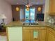 Kitchen with granite countertops, wooden cabinetry, and a view of the lush green outdoors through a large window at 2327 Addison Ave, Clermont, FL 34711